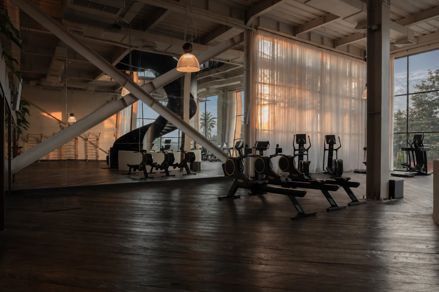 Rowing machines beside the mirrored wall, spiral staircase and tall curtained windows.