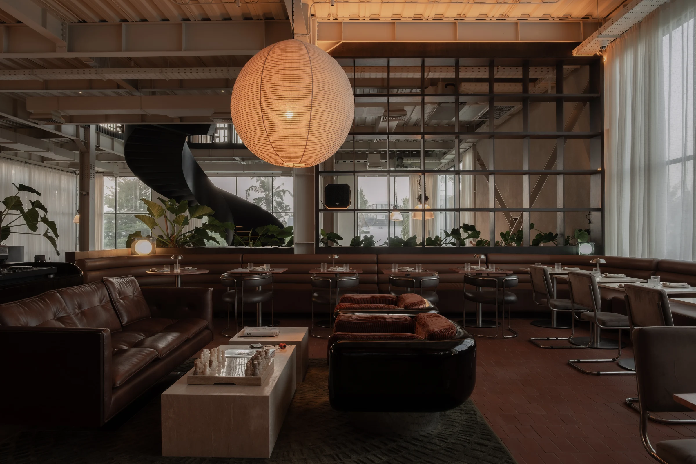 Leather sofas and a record console beneath a glowing lantern, seen across the lounge.