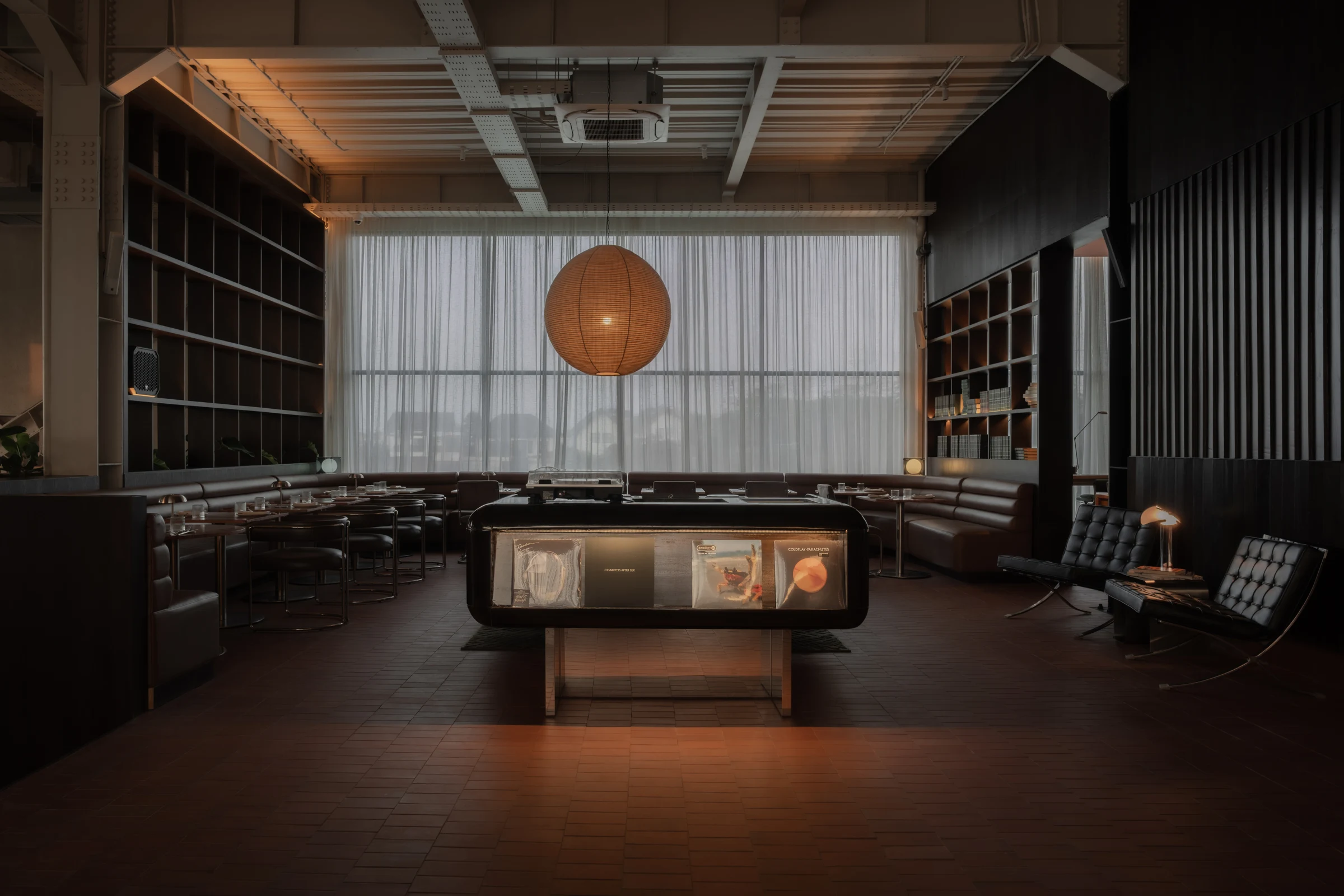 A glowing paper lantern above a record console and leather seating.